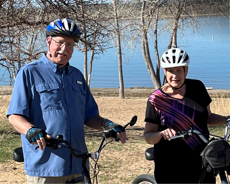 Mike, a Rx CAMZYOS® (mavacamten) patient, smiling with his wife, Amy on their bikes